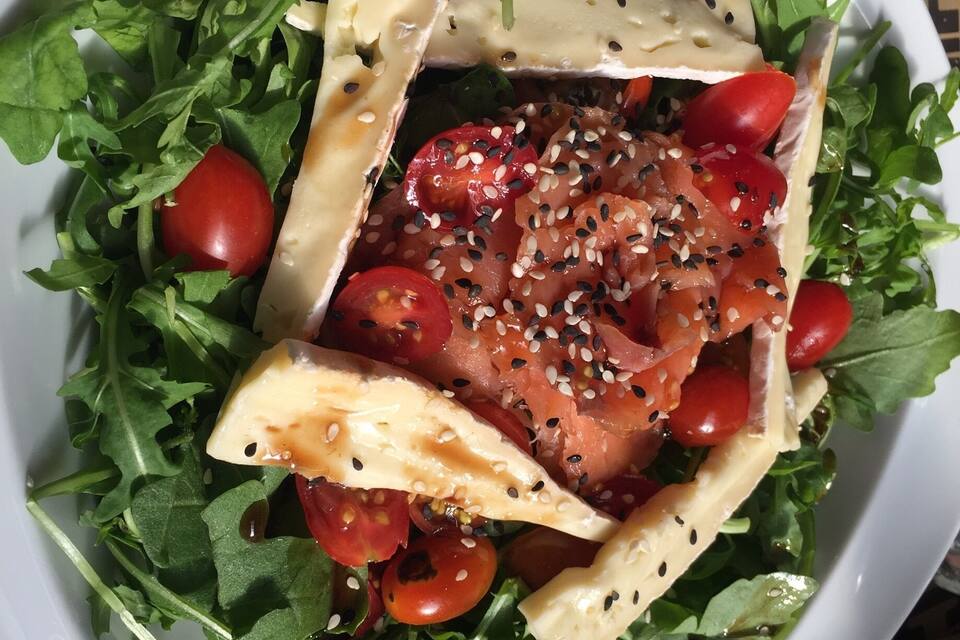 A salad with arugula, cherry tomatoes, and cheese on a white plate.