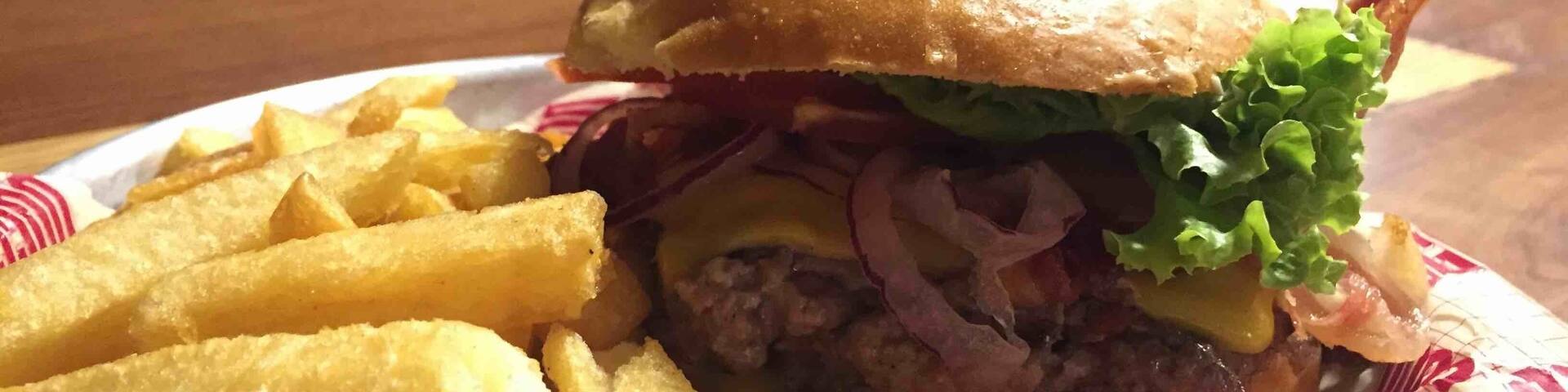 A burger with fries on a paper plate.