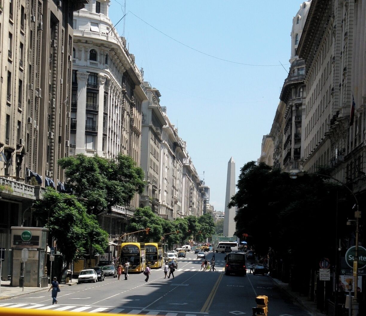 Ruas movimentadas da cidade com edifícios históricos, um obelisco imponente e um elétrico.