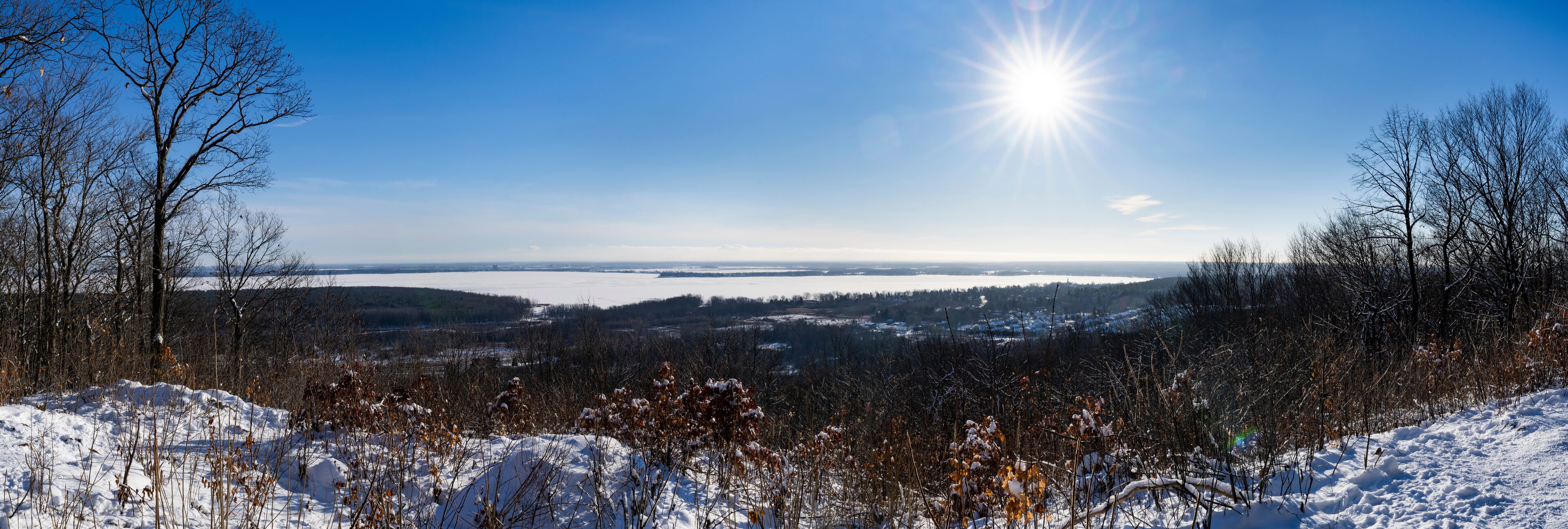 A snowy landscape with a clear blue sky and the sun shining.