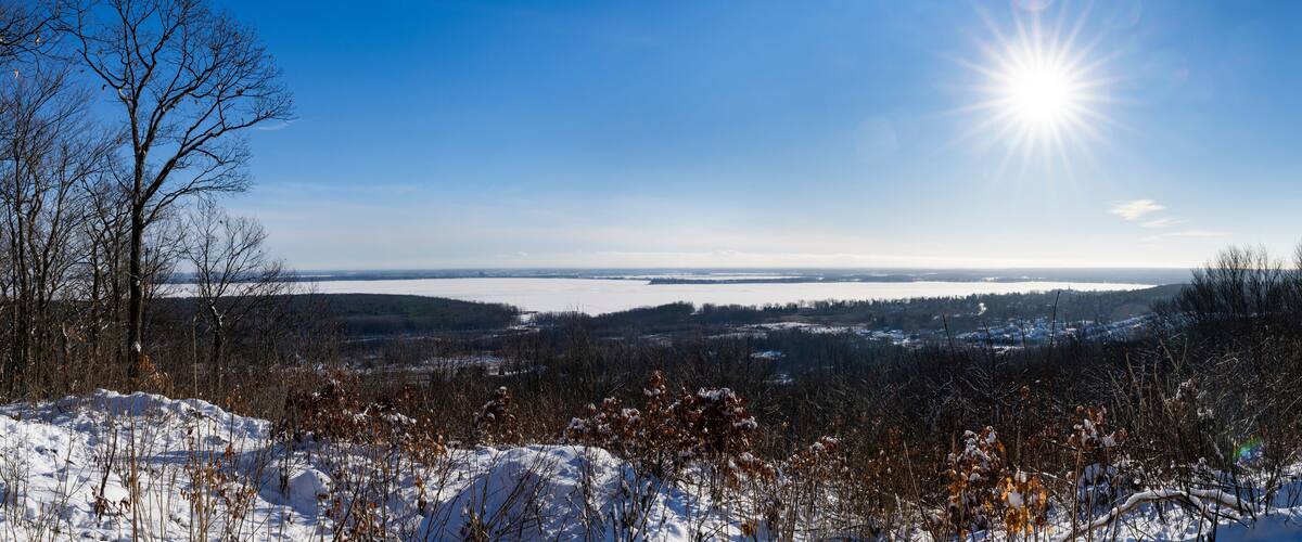 A snowy landscape with a clear blue sky and the sun shining.