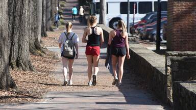 3 attractive college girls in athletic clothing walk near campus