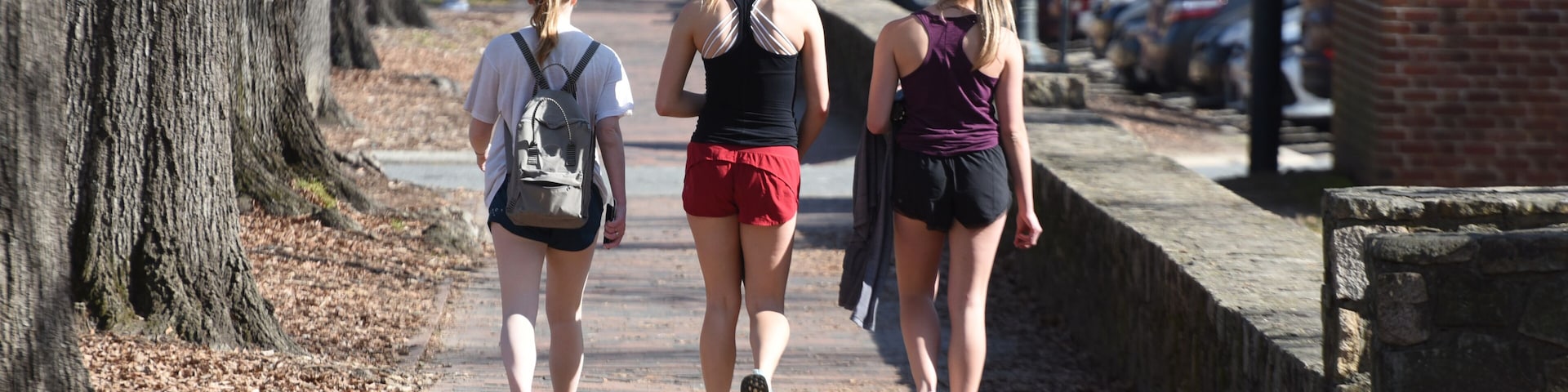 3 attractive college girls in athletic clothing walk near campus