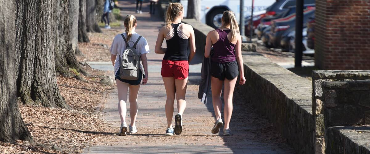 3 attractive college girls in athletic clothing walk near campus