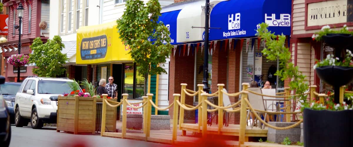 A street with a yellow storefront, a blue awning, and a brick building.