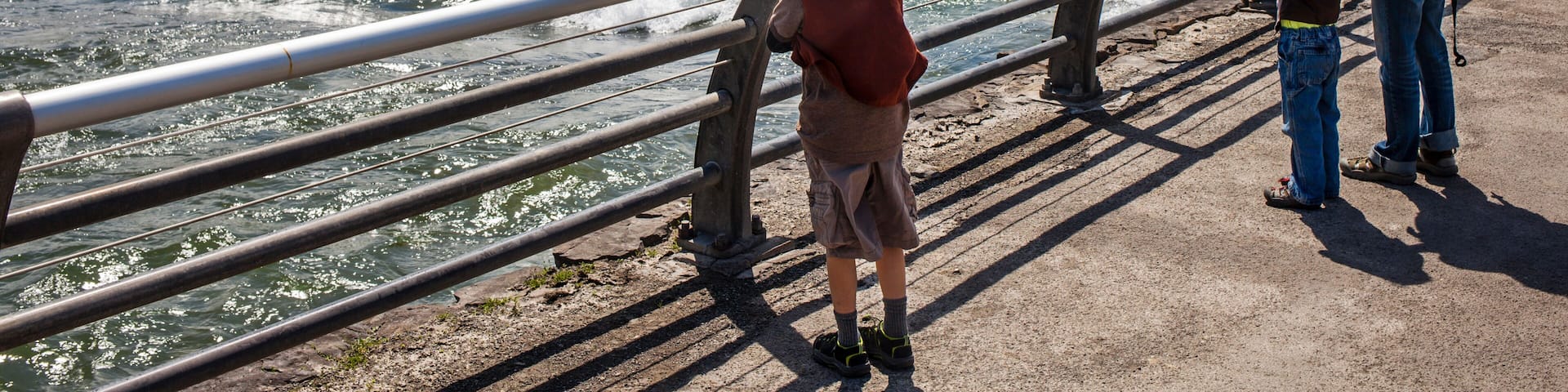 Mother standing beside Niagara Falls barrier with two little sons and baby daughter