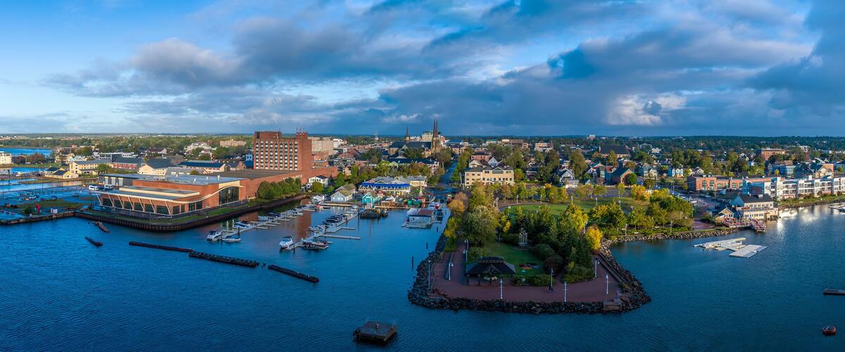 A coastal cityscape with a marina, historic buildings, and a prominent church spire.