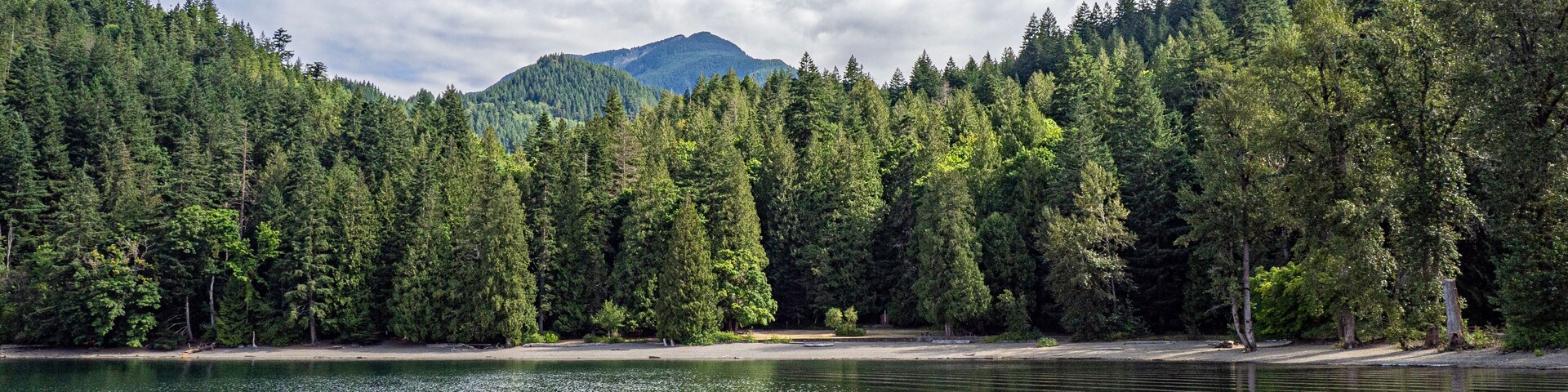 Harrison lake nearby areas within Sasquatch provincial park showing the rocky shoreline, forested backdrop, and glimpses of recreational spots, Harrison, BC, Canada