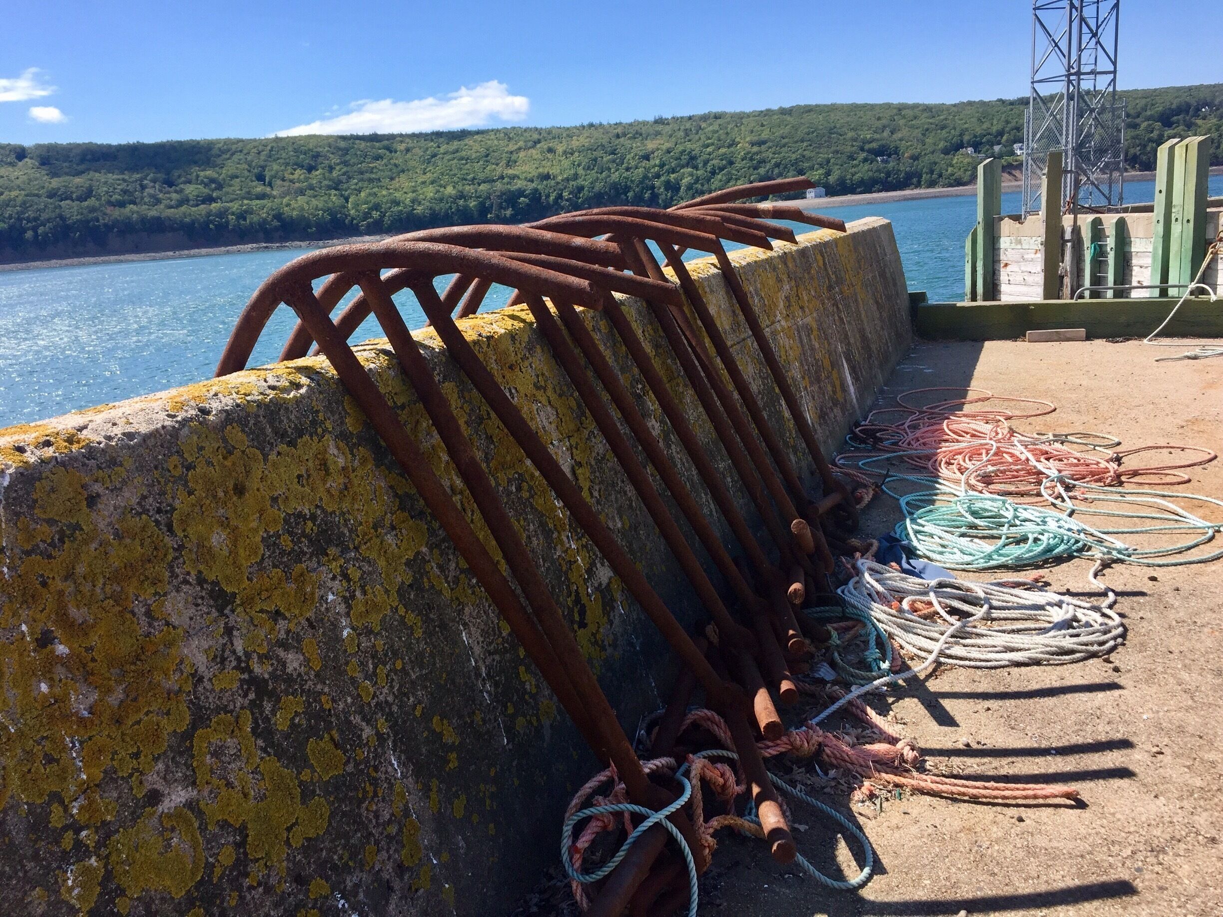 A concrete pier with rusted metal railings and colorful ropes.