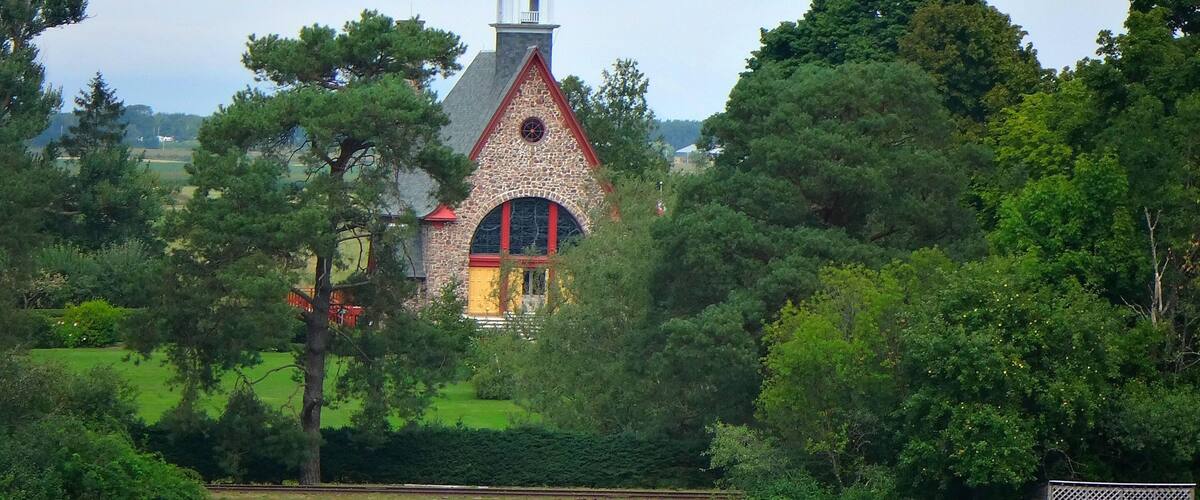 A church with a steeple, surrounded by lush greenery and a well-maintained lawn.