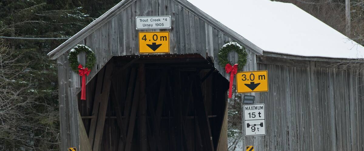 A wooden covered bridge with signs indicating a height limit of 4.0 meters and a maximum vehicle length of 15 meters.