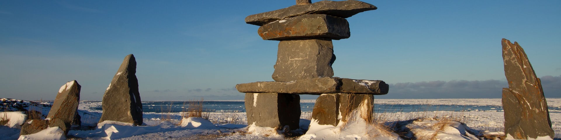 A stone structure in a snowy landscape with a clear blue sky.