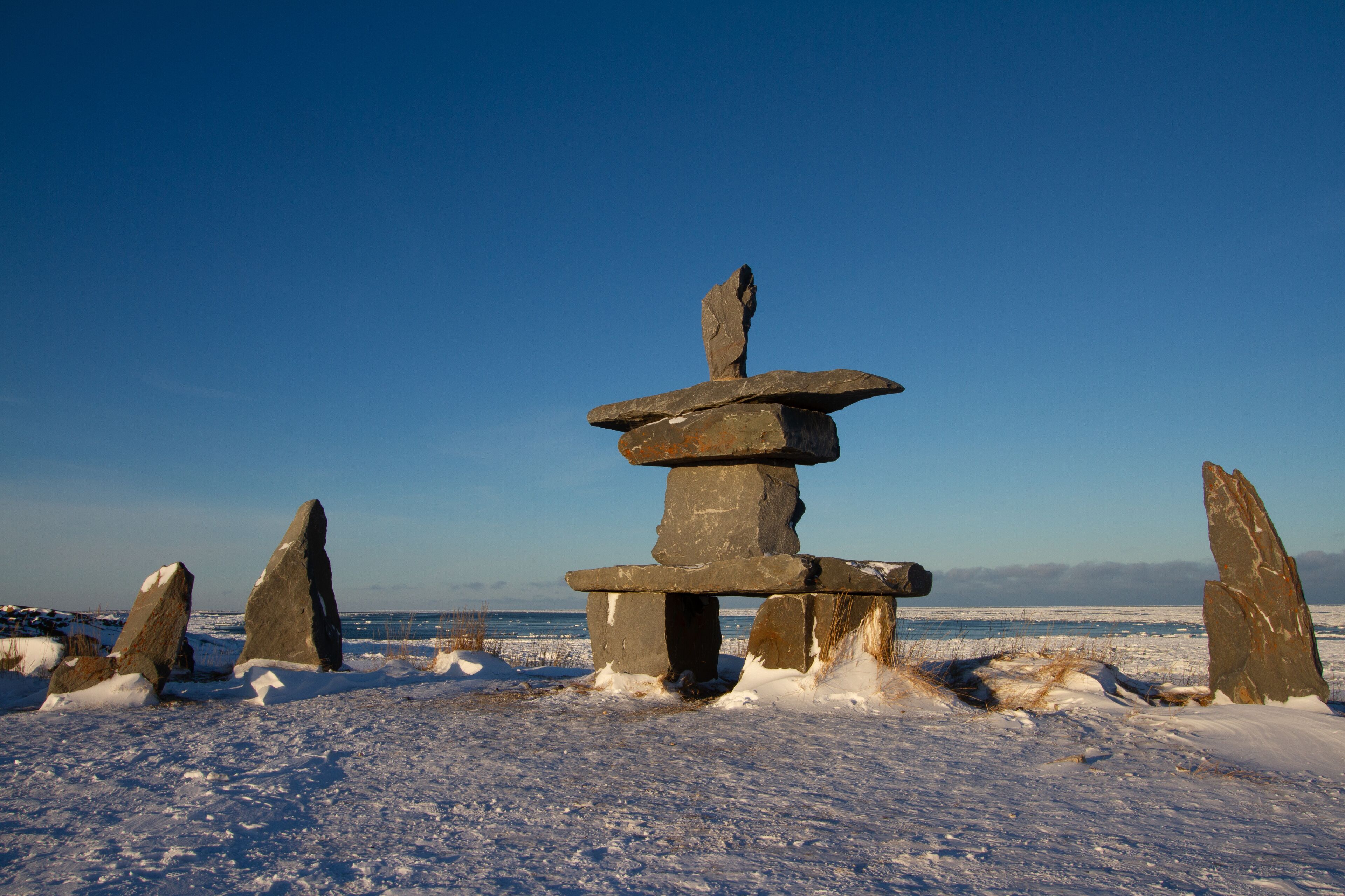 A stone structure in a snowy landscape with a clear blue sky.