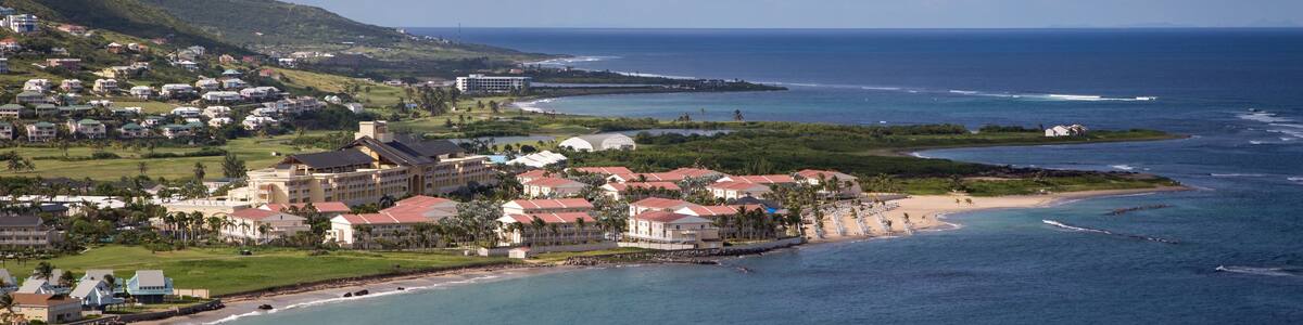 A coastal town with buildings near the beach and a mountain in the background.