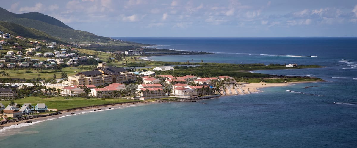 A coastal town with buildings near the beach and a mountain in the background.