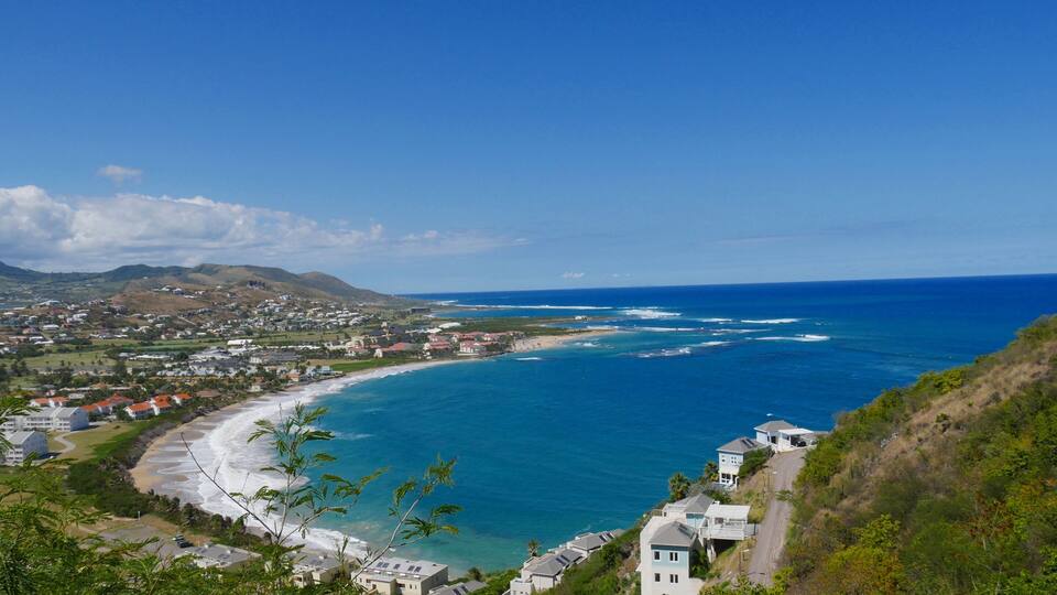 A coastal town with a beach, ocean, and hills.