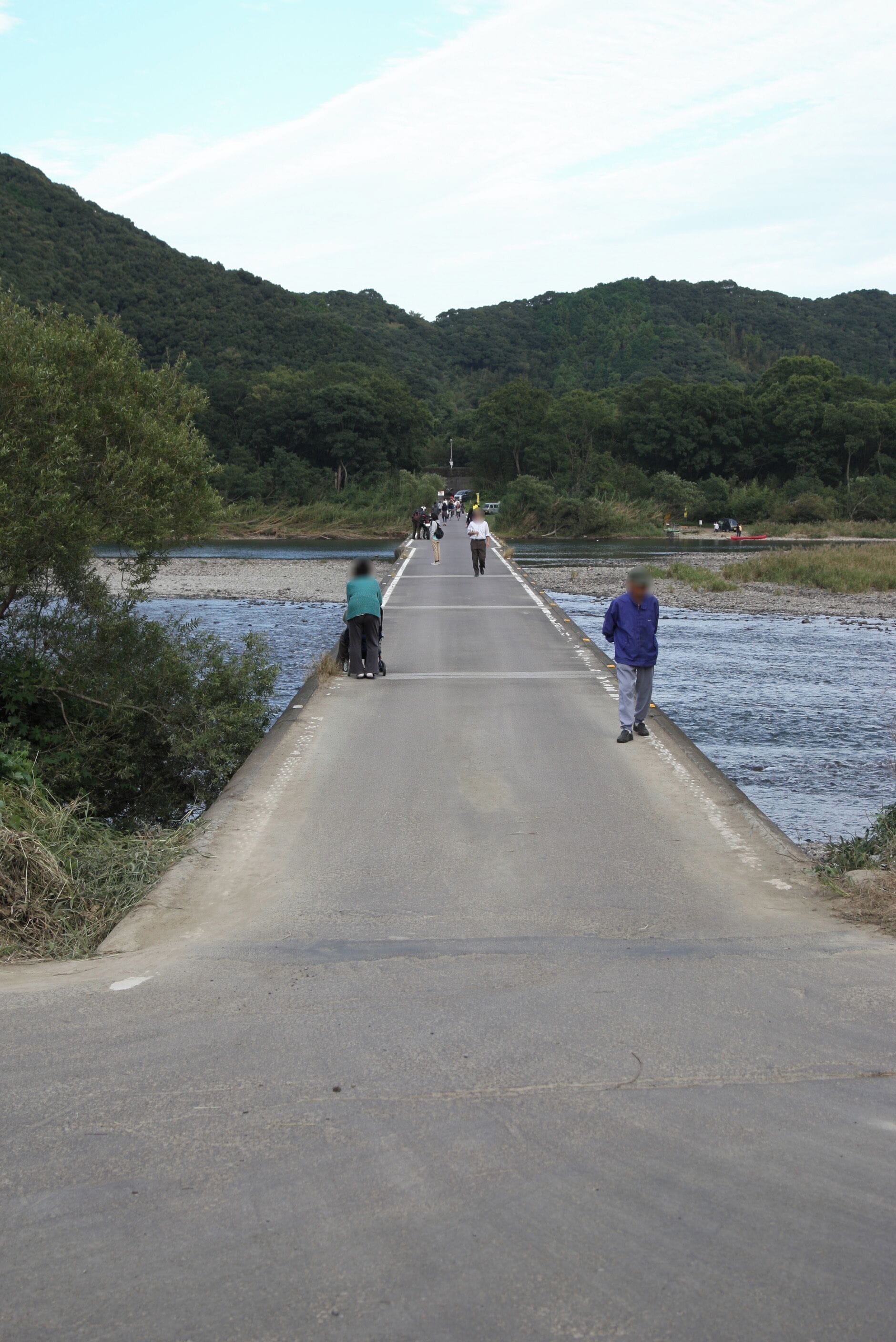 Un puente sobre un río, con gente caminando, rodeado de colinas verdes.