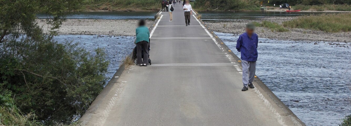 Un puente sobre un río, con gente caminando, rodeado de colinas verdes.