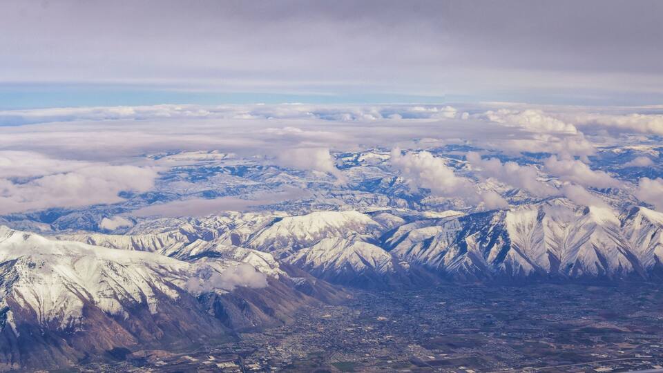 Snow-covered mountains, a valley, and a cityscape.