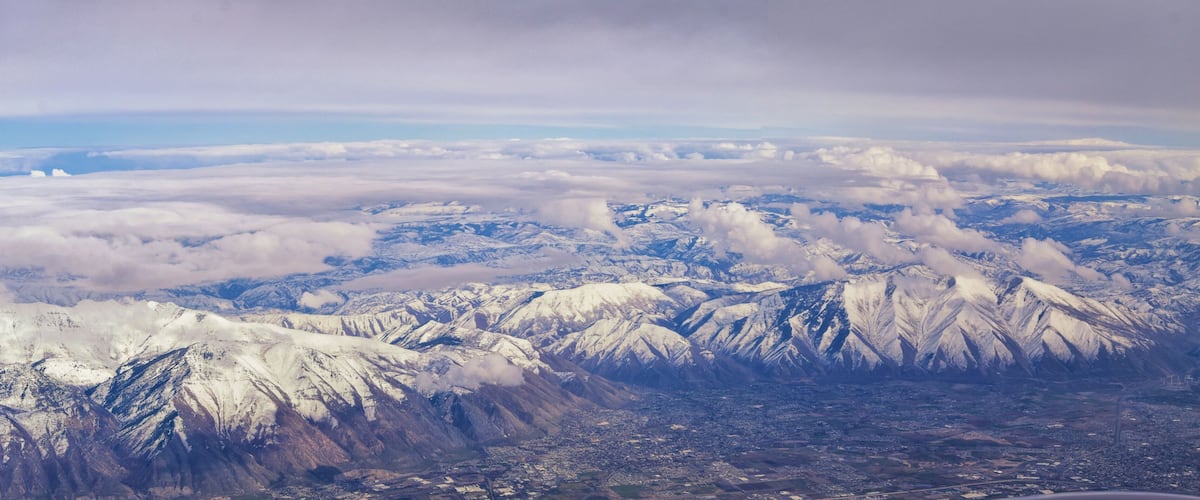 Snow-covered mountains, a valley, and a cityscape.