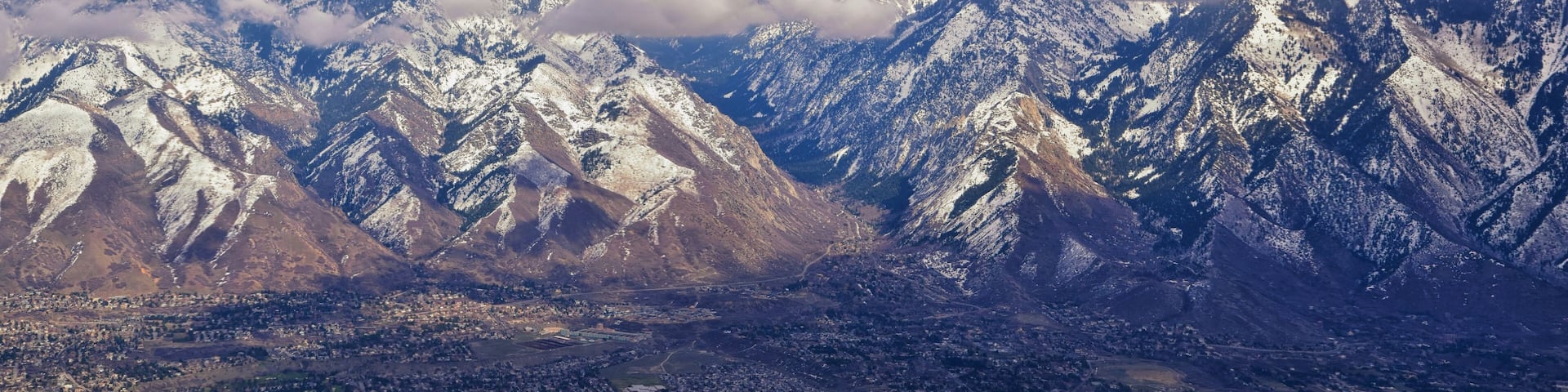 Aerial view from airplane of the Wasatch Front Rocky Mountain Range with snow capped peaks in winter including urban cities of Provo, Farmington Bountiful, Orem and Salt Lake City. Utah. United States