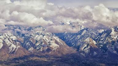 Aerial view from airplane of the Wasatch Front Rocky Mountain Range with snow capped peaks in winter including urban cities of Provo, Farmington Bountiful, Orem and Salt Lake City. Utah. United States