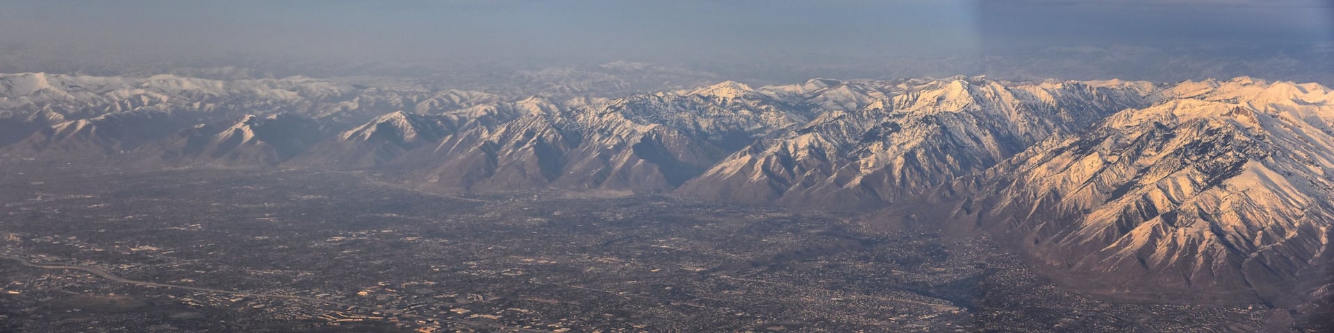Aerial view from airplane of the Wasatch Front Rocky Mountain Range with snow capped peaks in winter including urban cities of Provo, Farmington Bountiful, Orem and Salt Lake City. Utah. United States