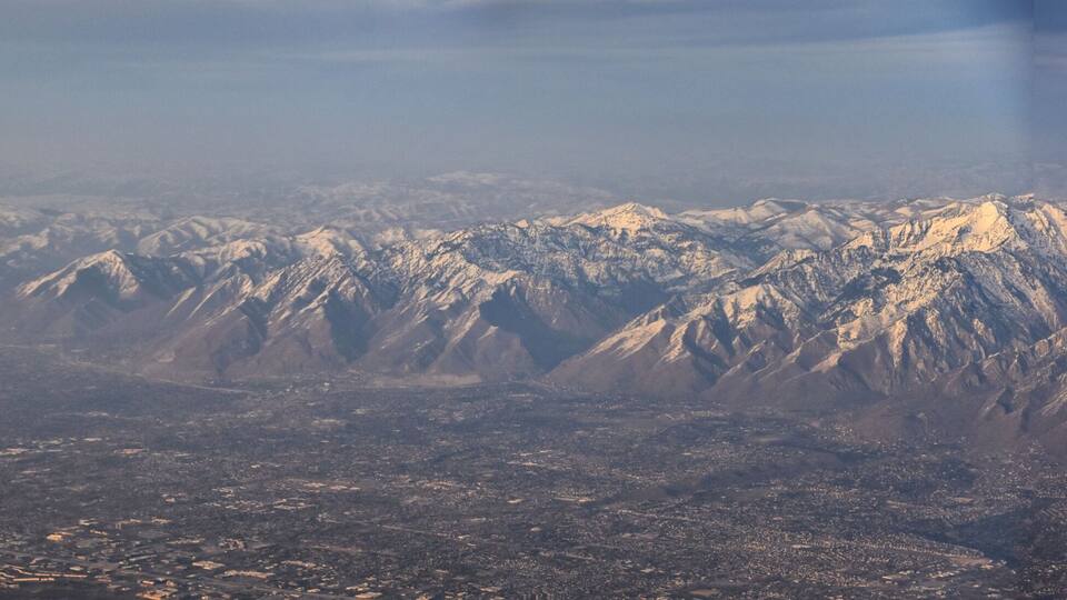 A snow-covered mountain range with a city in the foreground.