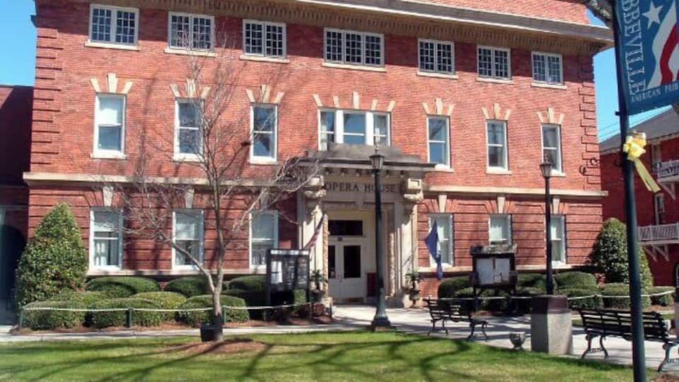 A red brick building with a sign reading "Opera House" and a flagpole with a flag.