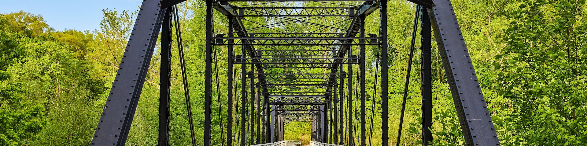Blue sky, dark metal bridge, black, train bridge style, wooden plank board walkway