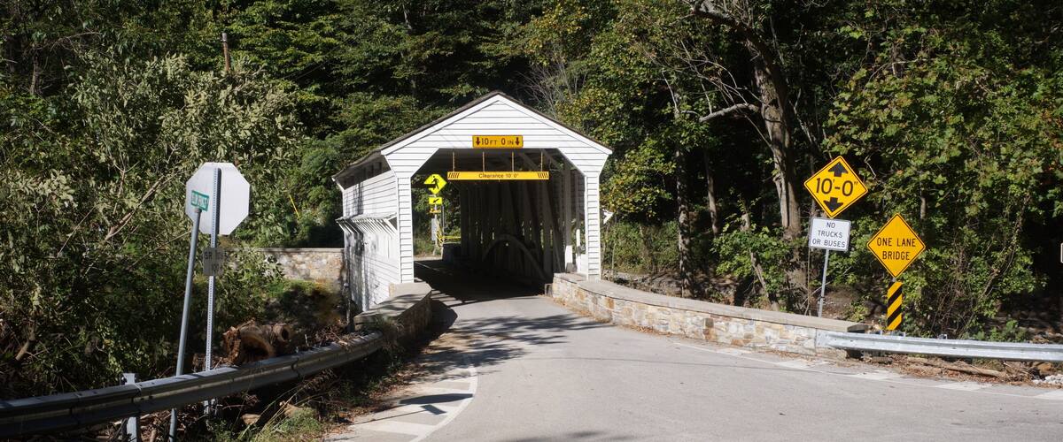 White Wooden Covered Bridge with Greenery in Sunlight