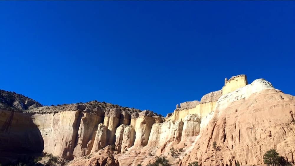 Un canyon accidenté aux formations rocheuses stratifiées, sous un ciel bleu limpide.