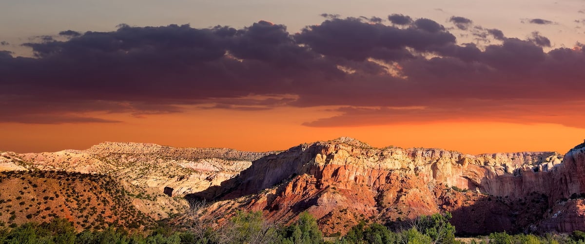 A rugged mountain range with prominent rock formations during sunset.
