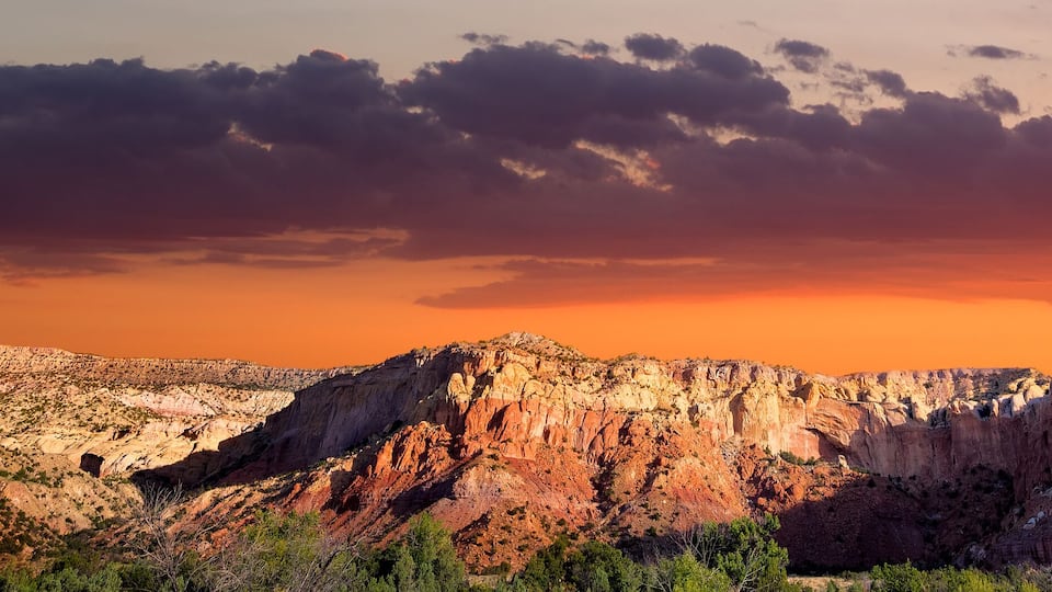 A rugged mountain range with prominent rock formations during sunset.