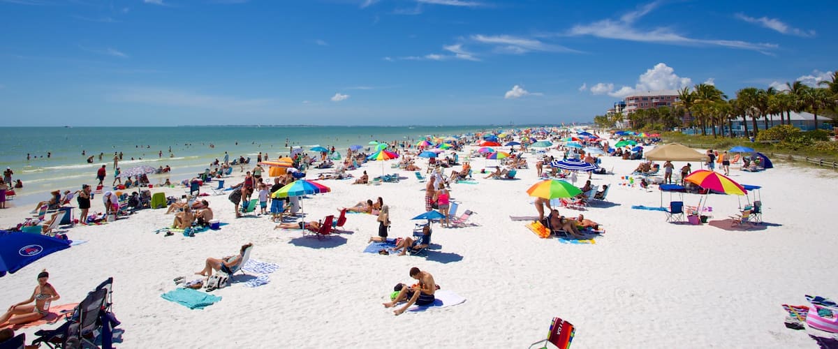 A crowded beach with people sunbathing and swimming.