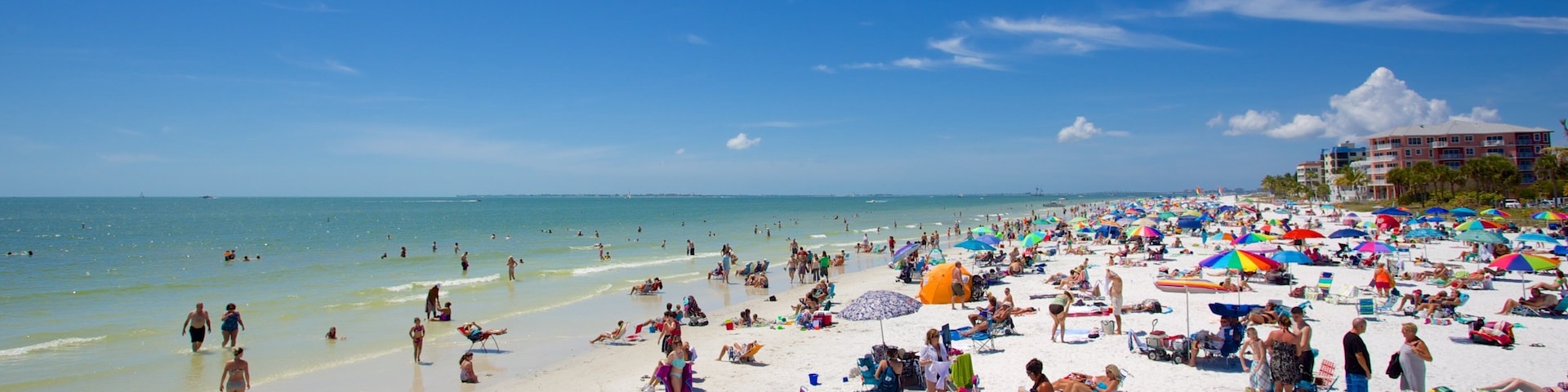 A crowded beach with people sunbathing and swimming.