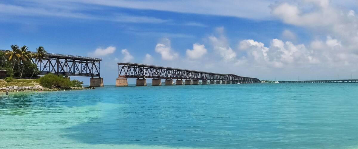 A coastal bridge over turquoise waters with clear skies.