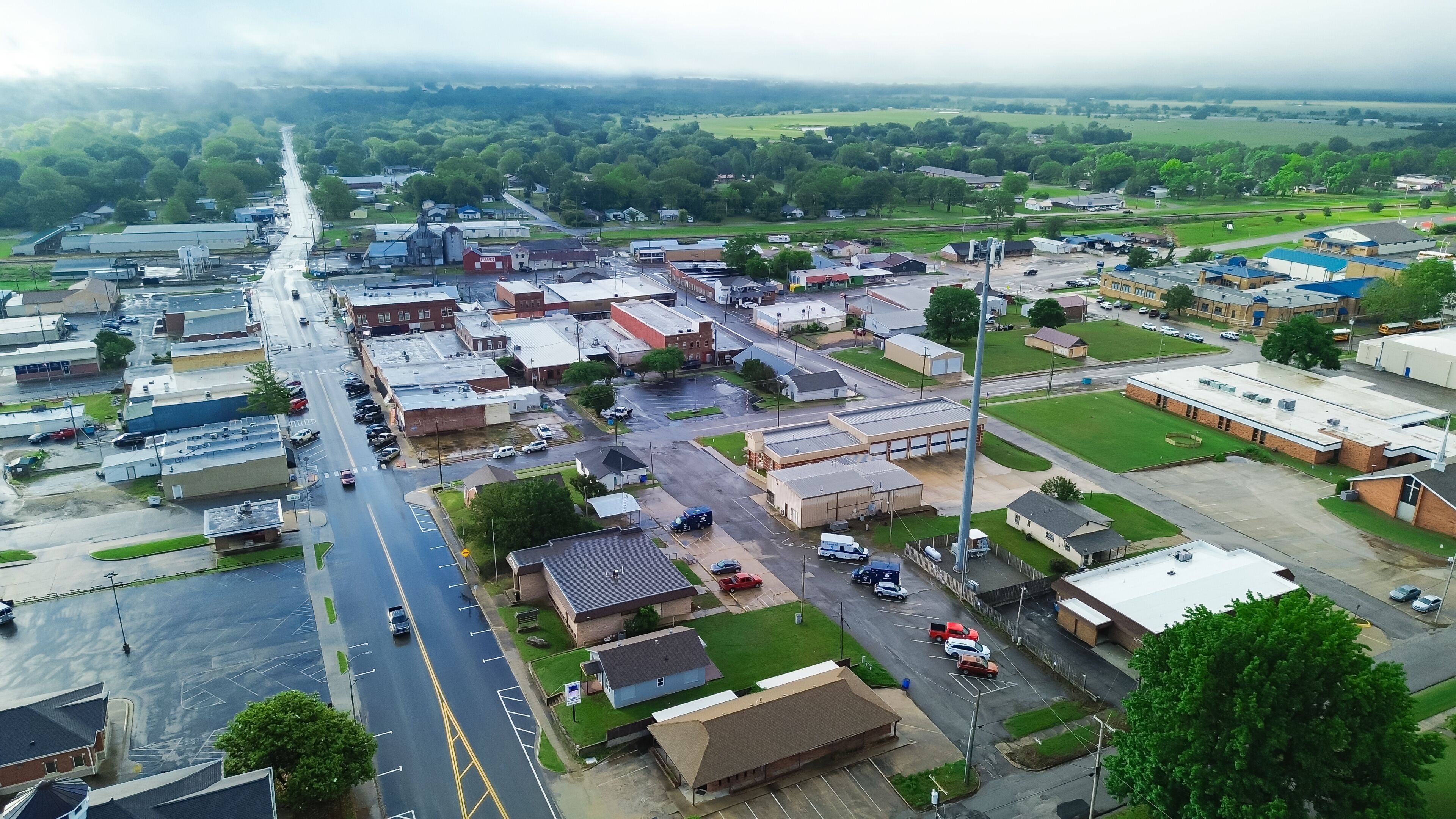 Gentry avenue along historic downtown of Checotah in McIntosh County, Oklahoma under foggy misty morning, aerial view small town with red brick buildings, antique malls, quiet street early summer