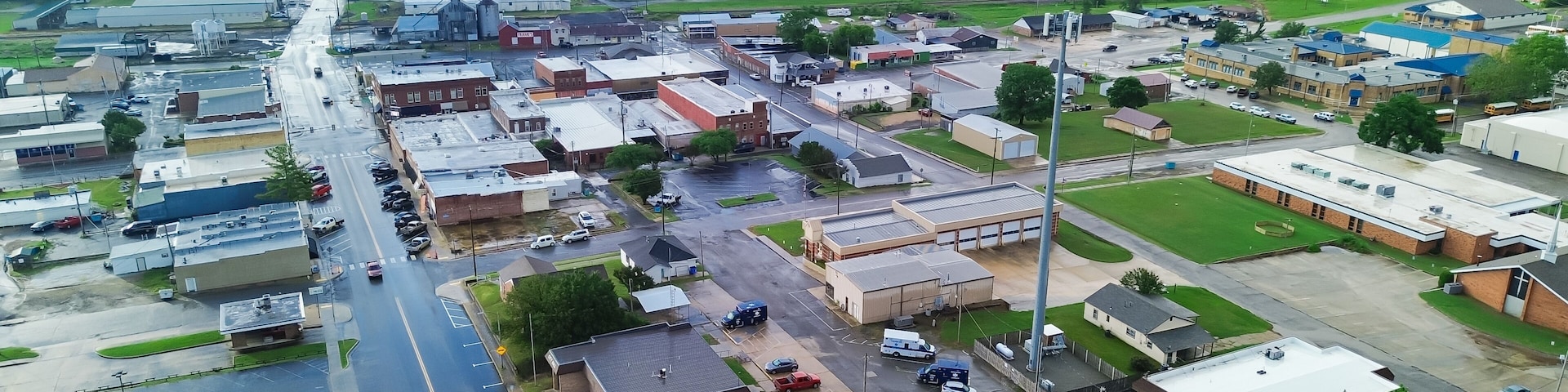 Gentry avenue along historic downtown of Checotah in McIntosh County, Oklahoma under foggy misty morning, aerial view small town with red brick buildings, antique malls, quiet street early summer