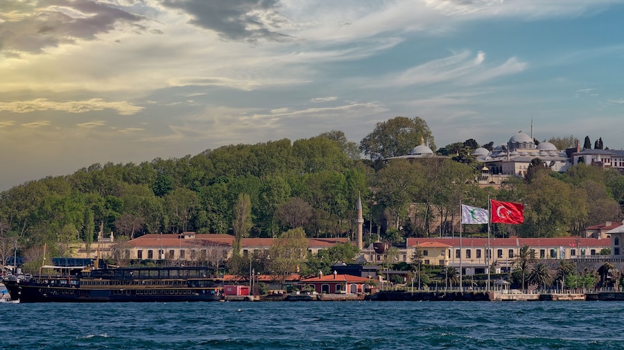 View from Galataport overlooking Bosphorus strait with sailing ferry boat and Topkapi Palace in the far end before sunset, Istanbul, Turkey