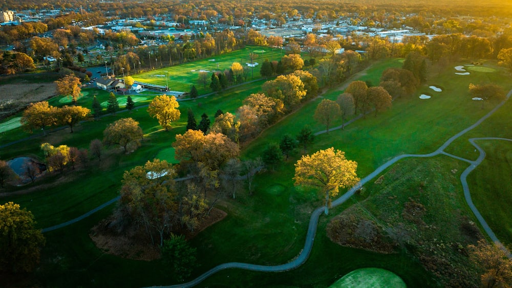Vue aérienne d’un terrain de golf avec une ville en arrière-plan.