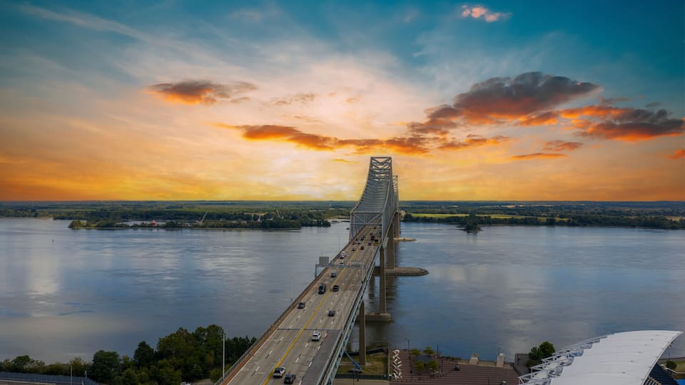 A bridge over a river with a sunset sky.