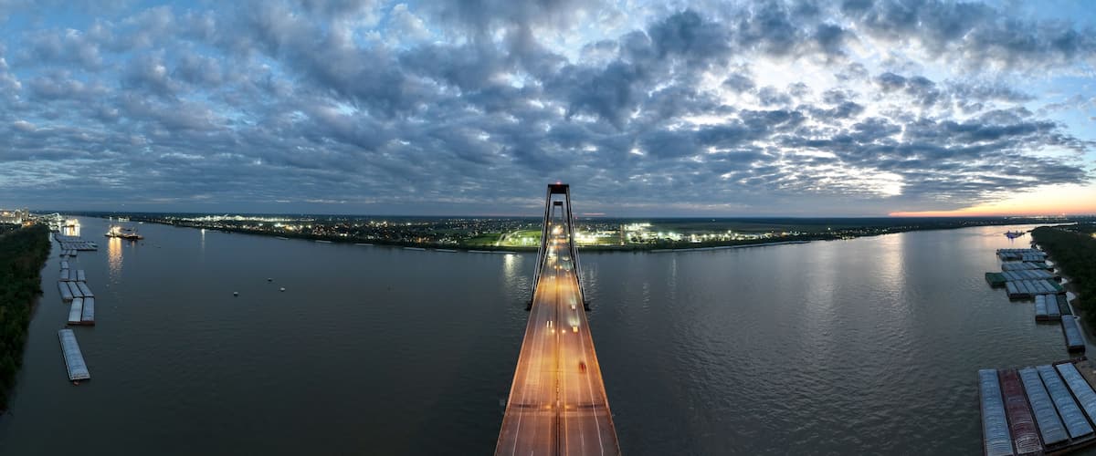 A river with a bridge, boats, and city lights in the distance.