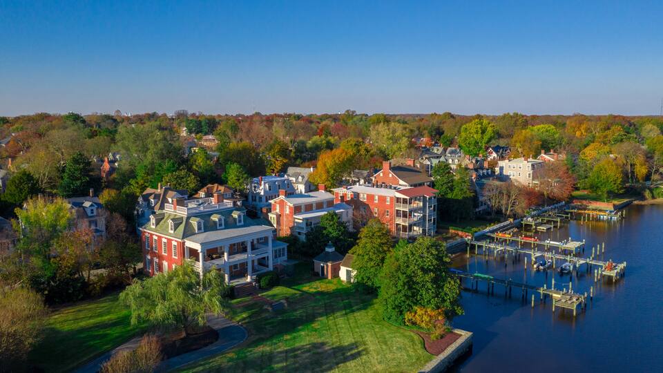 A riverside residential area with houses, docks, and a clear blue sky.