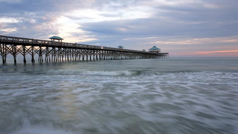 Folly Beach mit einem Sonnenuntergang, BrĂŒcke und Sandstrand