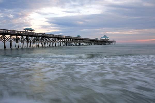 Folly Beach featuring a sandy beach, a bridge and a sunset