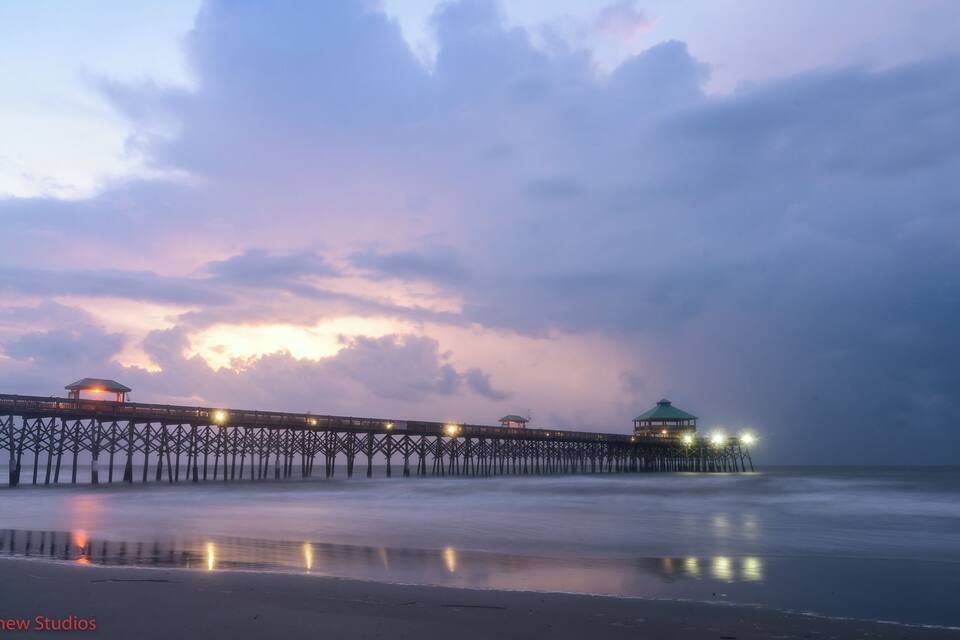 Un muelle que se adentra en el agua, con luces y un pabellón al final.
