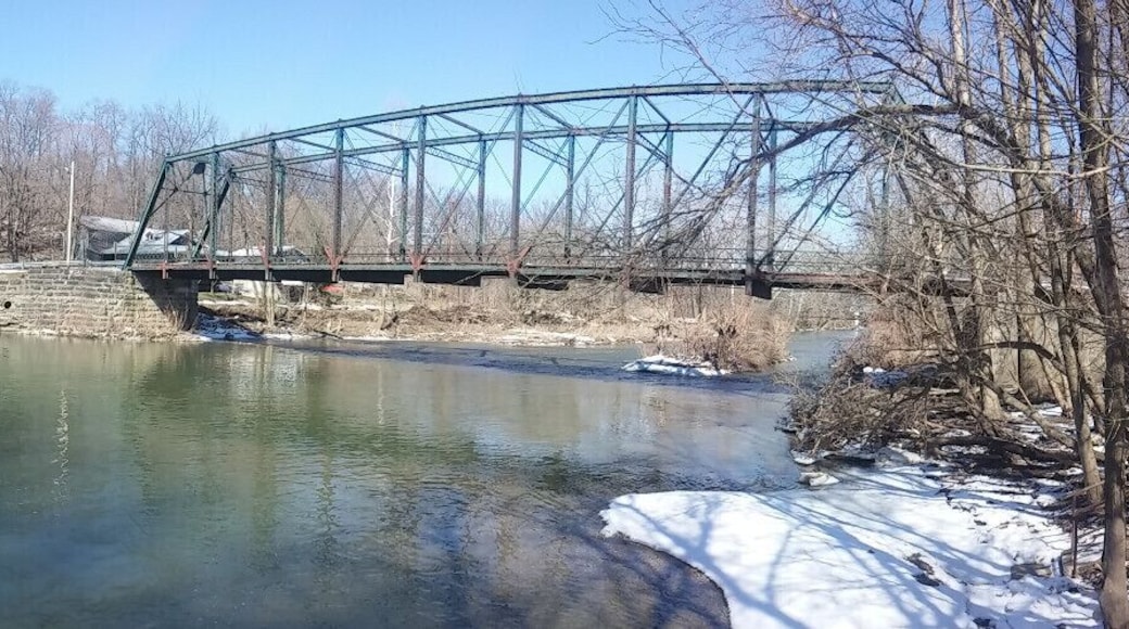 A view of the dam and mill from across the river. This view also includes the Indian Mill bridge, a Pin-connected, 10-panel Pratt through truss bridge built in 1913.