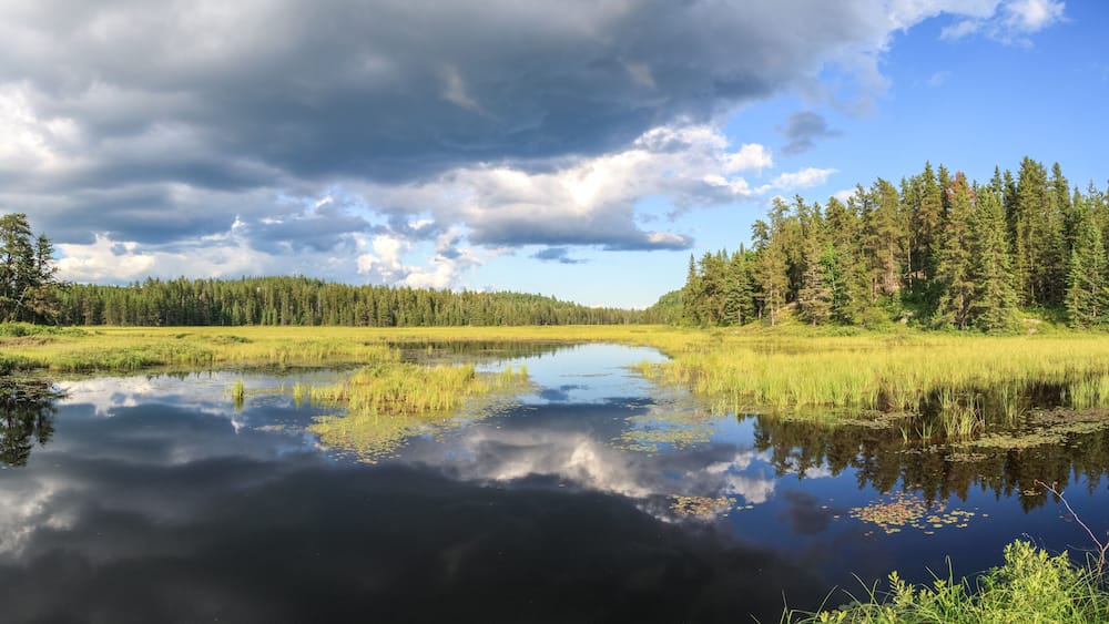 Blue mirror lake reflections of clouds and landscape. Sudbury, Ontario, Canada.