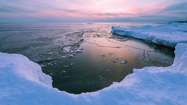 Shoreline of Lake Superior formed by snowbank in winter at sunset